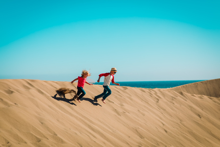 happy boy and girl play in sand dunesの写真素材