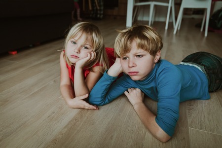 little boy and girl bored staying homeの写真素材