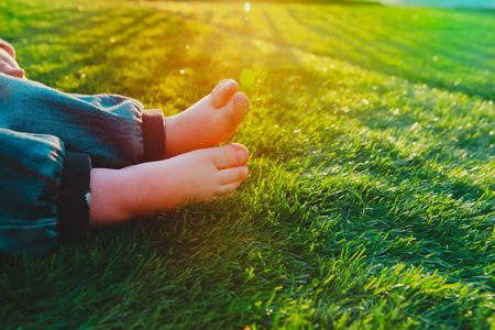 little girl bare foot on grass at sunset natureの写真素材