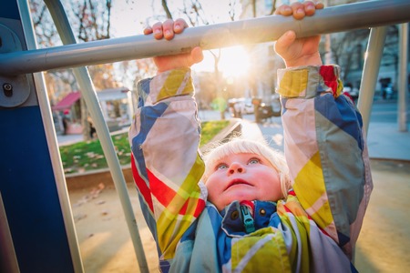 little girl play on monkey bars in city playgroundの写真素材