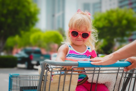 shopping with kids- cute little girl in shopping cart in the cityの写真素材