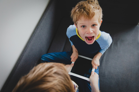 computer addiction - father taking touch pad from angry childの写真素材