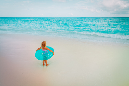 cute little girl with inflatable life ring go swim at beachの写真素材