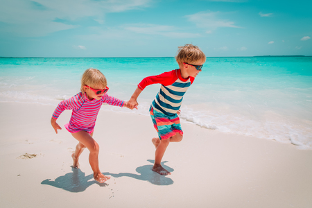 little boy and girl run at beach, kids play on vacationの写真素材