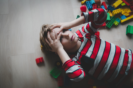 kid tired of playing, exhaustion with toys scattered aroundの写真素材
