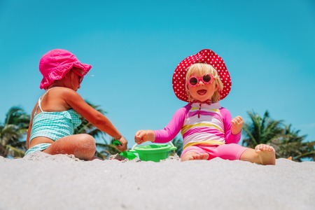 cute little girls play with sand on beachの写真素材
