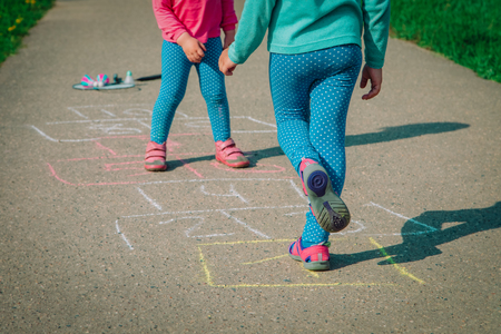 little girls play hopscotch on playground, kids outdoorsの写真素材
