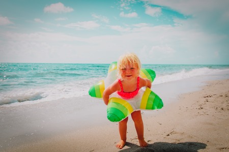 cute little girl with toy floating ring at beachの写真素材
