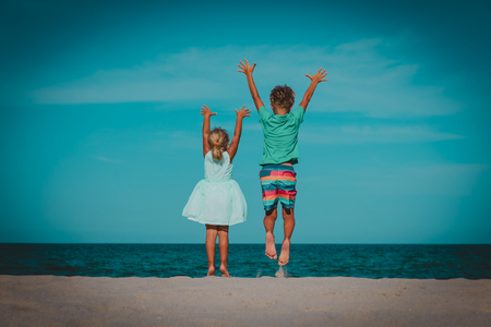happy boy and girl play on beach, kids jump and have funの写真素材