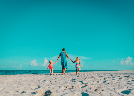 mother with little daughters walk on beach, family vacationの写真素材