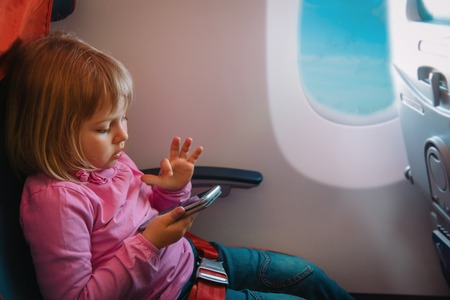 cute girl with mobile phone in flightの写真素材