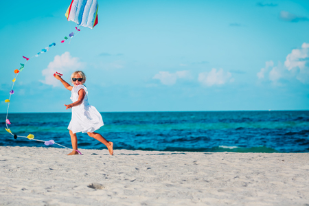 Little girl flying a kite at sky on beachの写真素材