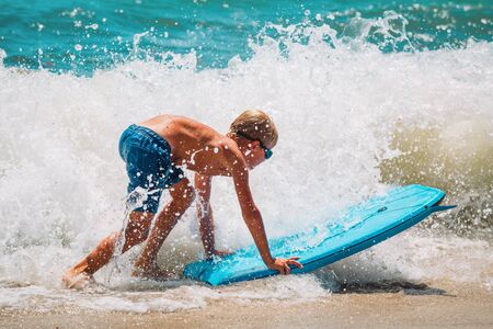 happy boy enjoy surfing at sea, kids play with water on vacaton