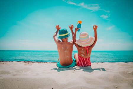 sun protection- little boy and girl with suncream at beachの写真素材