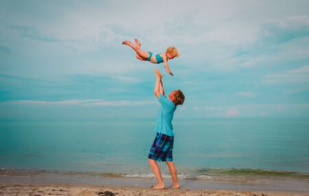 father and happy cute little daughter play at sky on beachの写真素材