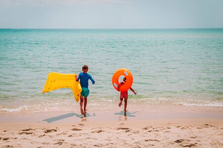 happy boy and girl with floaties run swim on beachの写真素材