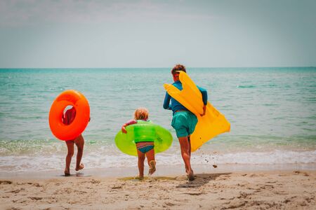 happy boy and girls with floaties run swim on beachの写真素材