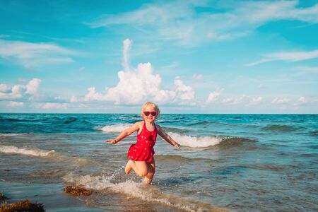 happy cute little girl play with waves on the beachの写真素材