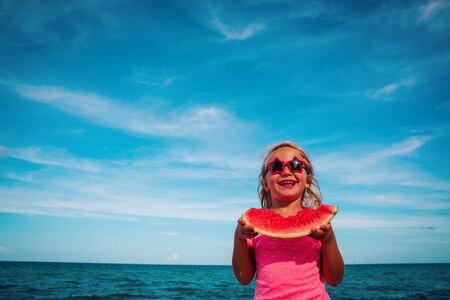 happy cute little girl eating watermelon at beachの写真素材