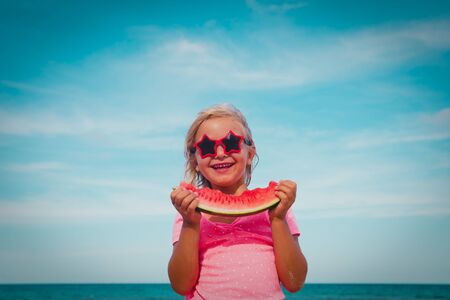 happy cute little girl eating watermelon at beachの写真素材