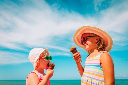 happy cute little girls eating ice cream on beachの写真素材