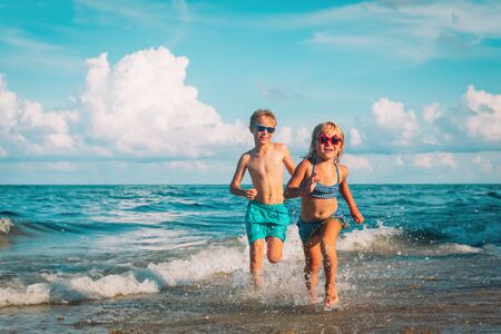 happy little girl and boy running at beachの写真素材