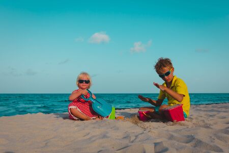 cute boy and girl play with sand on beachの写真素材