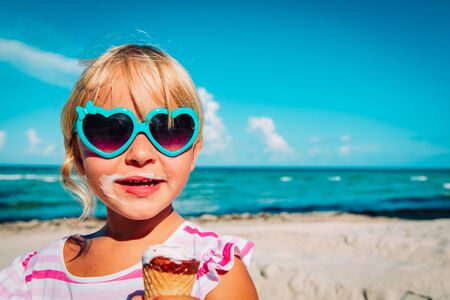 happy cute girl eating ice cream on beachの写真素材