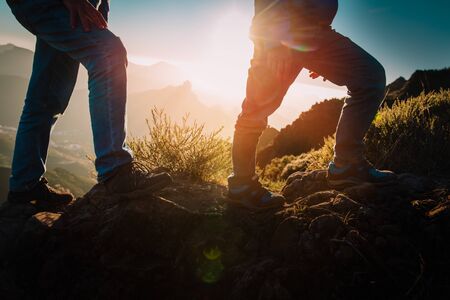 father and son hiking in mountains at sunset