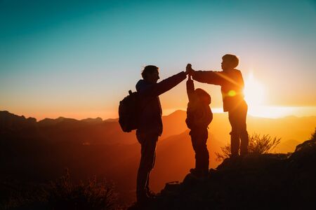 father with kids travel in sunset mountains, family high five in nature