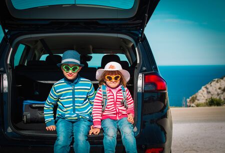 happy little boy and girl enjoy travel by car on sea coastの写真素材