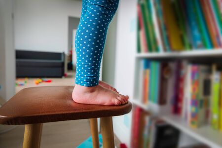 kids safety- little girl climb on chair at homeの写真素材