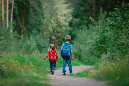 little boy and girl with backpacks going to school, kids walk in natureの写真素材