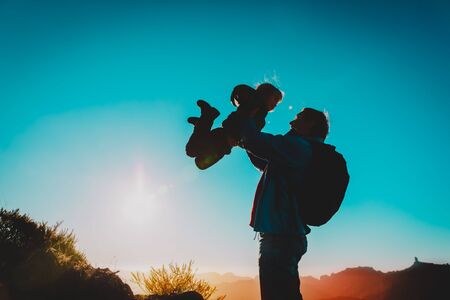 Father and little daughter enjoy travel in sunset mountains