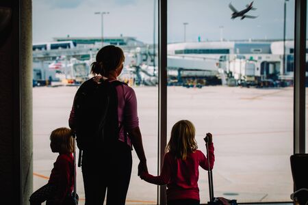 mother with kids and luggage looking at planes in airportの写真素材