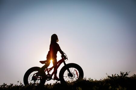 happy girl riding bike at sunset, active kidsの写真素材