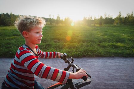 happy cute boy enjoy riding bike in sunset natureの写真素材