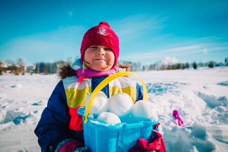 little girl making snowball in winter nature