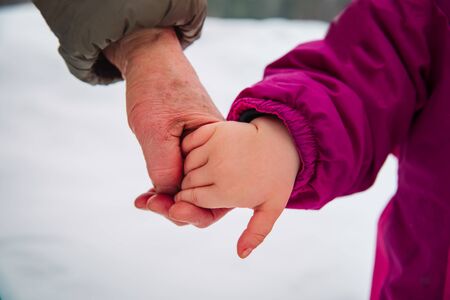 grandmother holding grandchild hand in winter nature