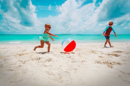 little girl and boy play ball on beachの写真素材