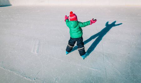happy little girl learning to skate in winterの写真素材
