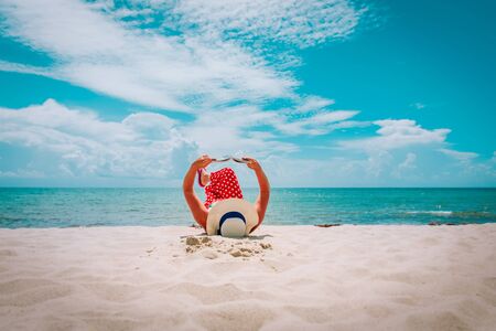 young woman reading book on tropical beach vacationの写真素材