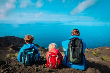 father with son and daughter looking at scenic view while travel in mountains near sea