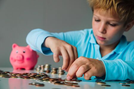 child counting money, boy put coins into piggy bank