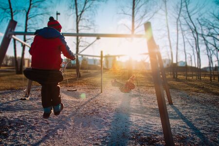 boy and girl on swings in outdoor playground, kids play outsideの写真素材
