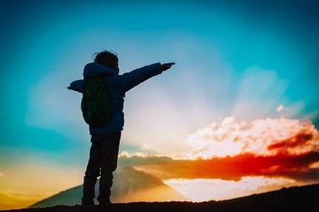Silhouettes of happy boy enjoy travel at sunset mountains