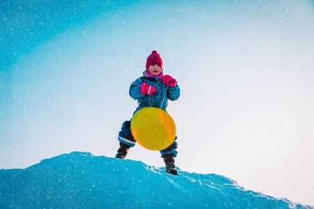 happy girl prepare for snow slide, winter kids activitiesの写真素材