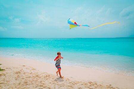 happy boy flying a kite on tropical beach, family at seaの写真素材