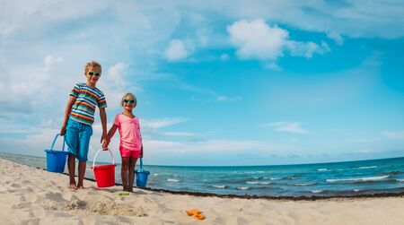 happy cute boy and girl play with sand on beachの写真素材