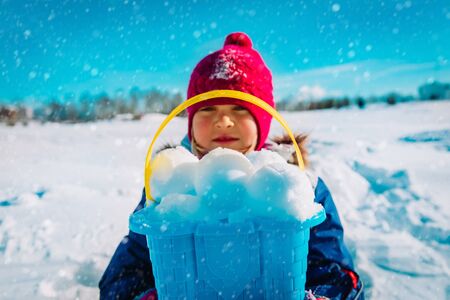 happy little girl making snowball in winter natureの写真素材